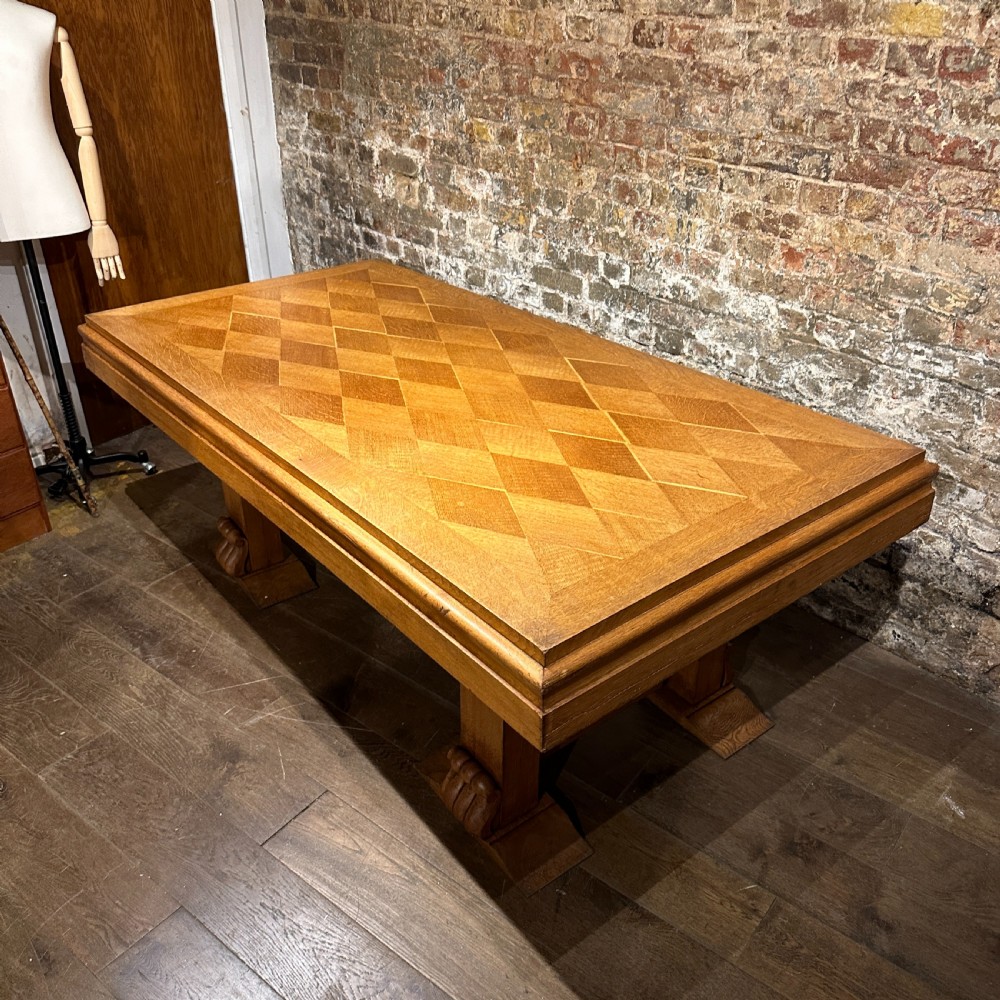 A large rectangular French Art Deco dining table featuring a geometric parquetry top and sturdy carved supports. View IV