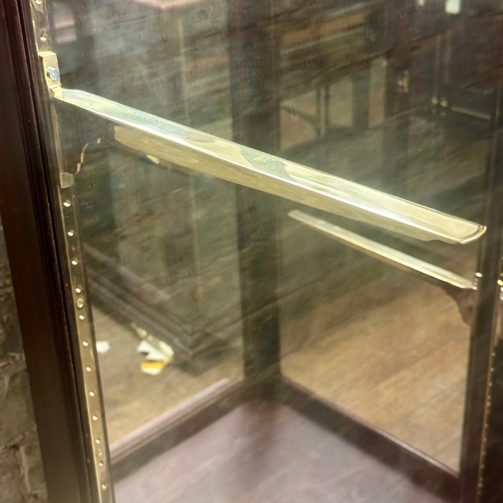 A tall 1920s mahogany shop display cabinet featuring full-length glass side panels, a glazed front door, internal shelf supports, and a solid timber plinth base. View III