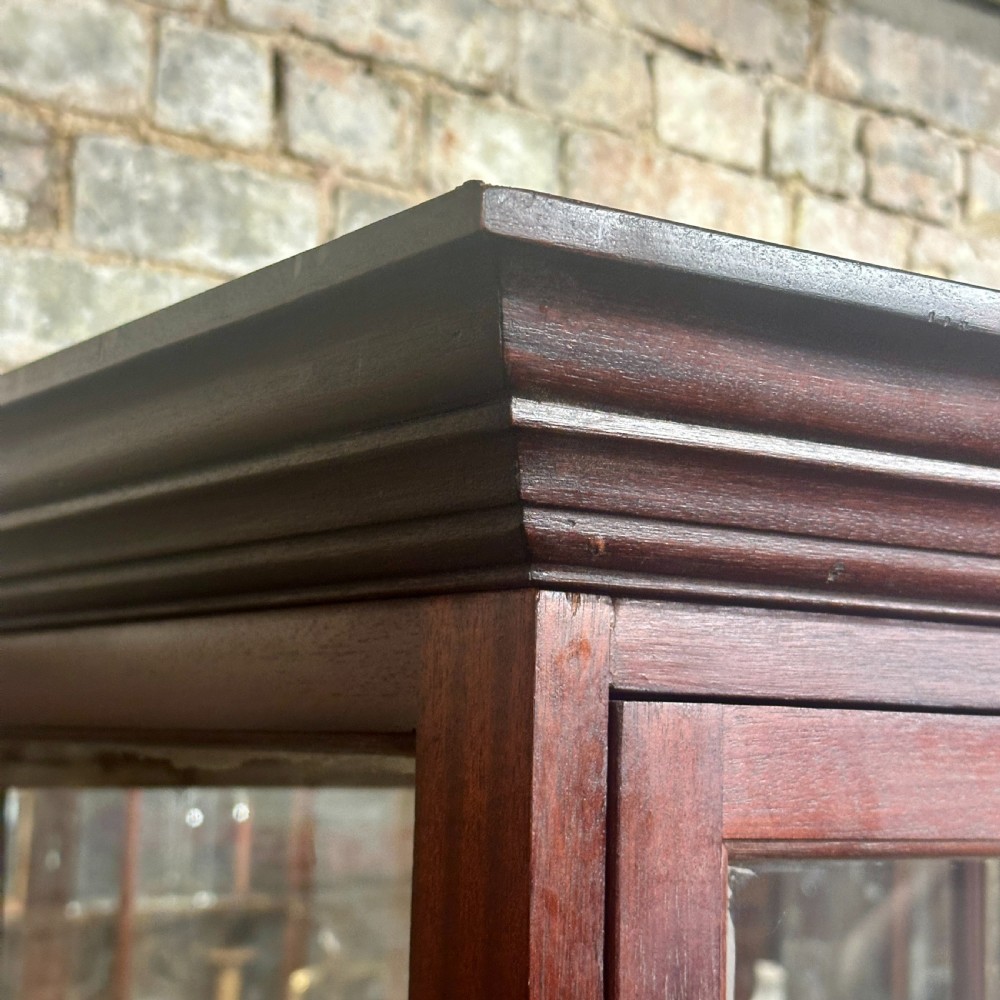 A tall 1920s mahogany shop display cabinet featuring full-length glass side panels, a glazed front door, internal shelf supports, and a solid timber plinth base. View IV