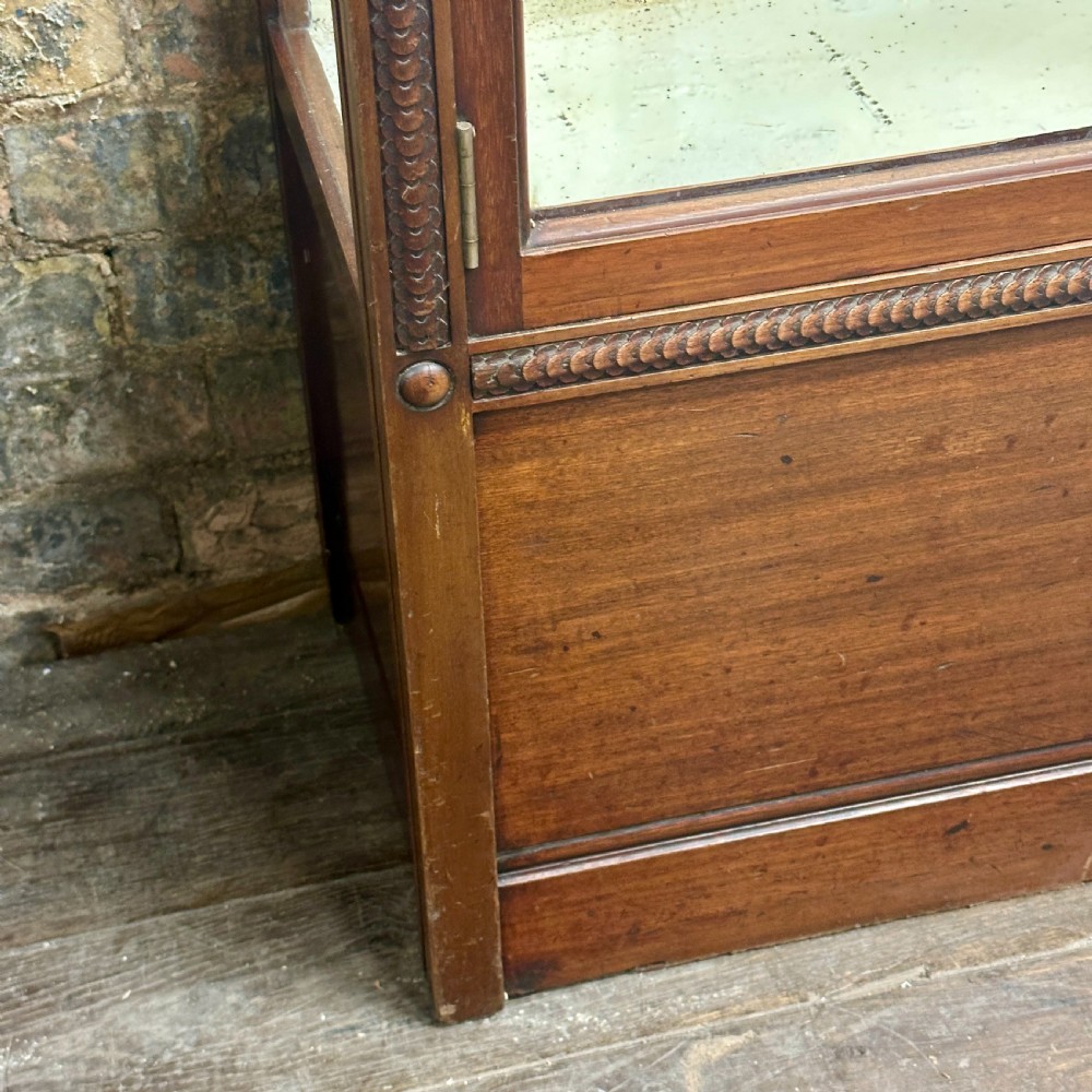 A tall dark mahogany glazed shop display cabinet featuring two full-length glass doors and internal brass ratchet supports. View II