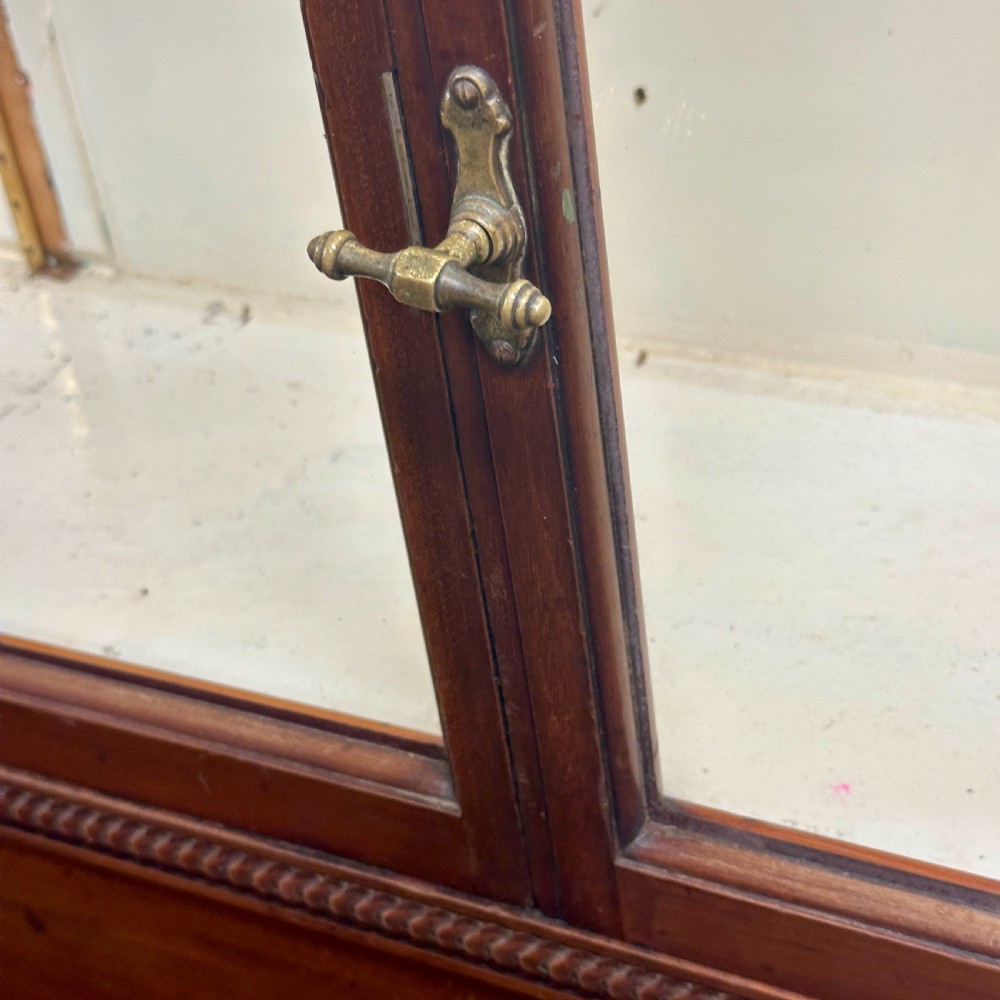 A tall dark mahogany glazed shop display cabinet featuring two full-length glass doors and internal brass ratchet supports. View III