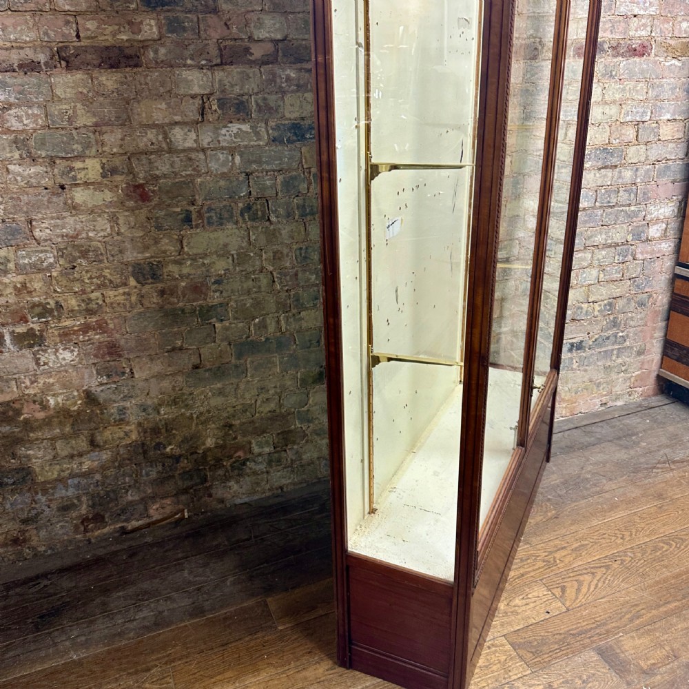 A tall dark mahogany glazed shop display cabinet featuring two full-length glass doors and internal brass ratchet supports. View IV