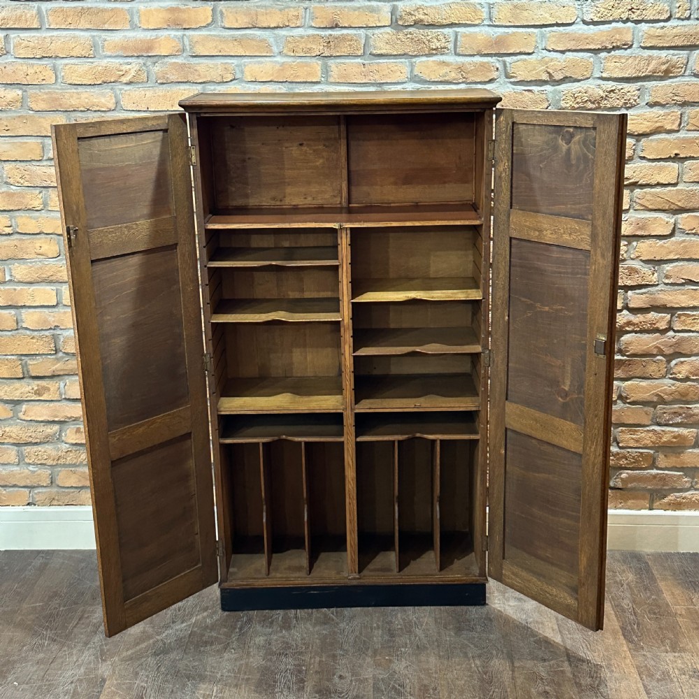 A vintage 1930s oak school cabinet featuring two doors with hand-painted institutional lettering and a crest. View II