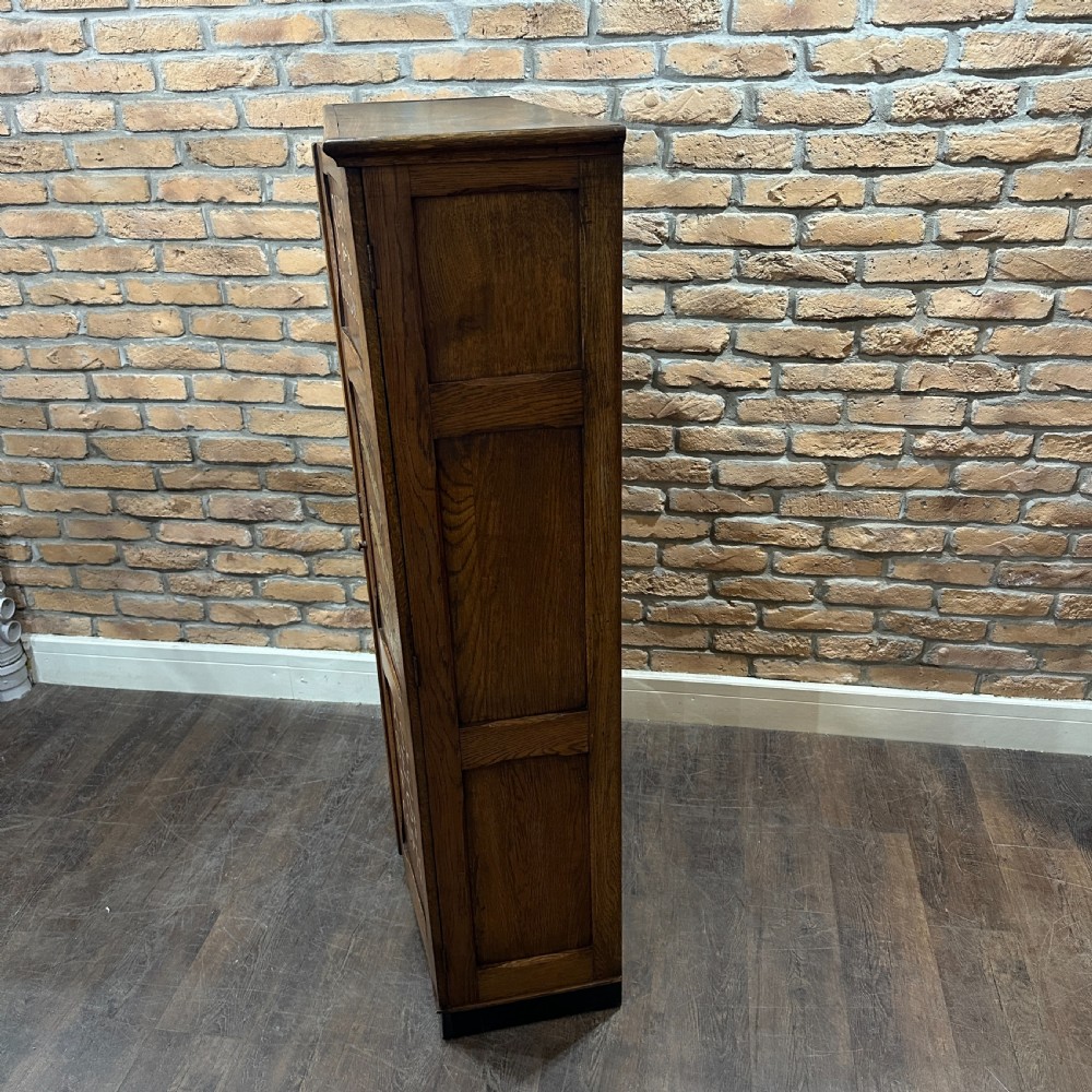 A vintage 1930s oak school cabinet featuring two doors with hand-painted institutional lettering and a crest. View V