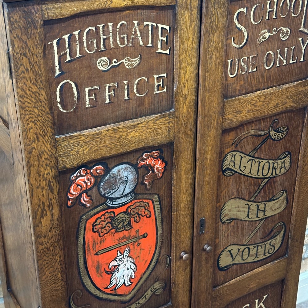 A vintage 1930s oak school cabinet featuring two doors with hand-painted institutional lettering and a crest. View VI