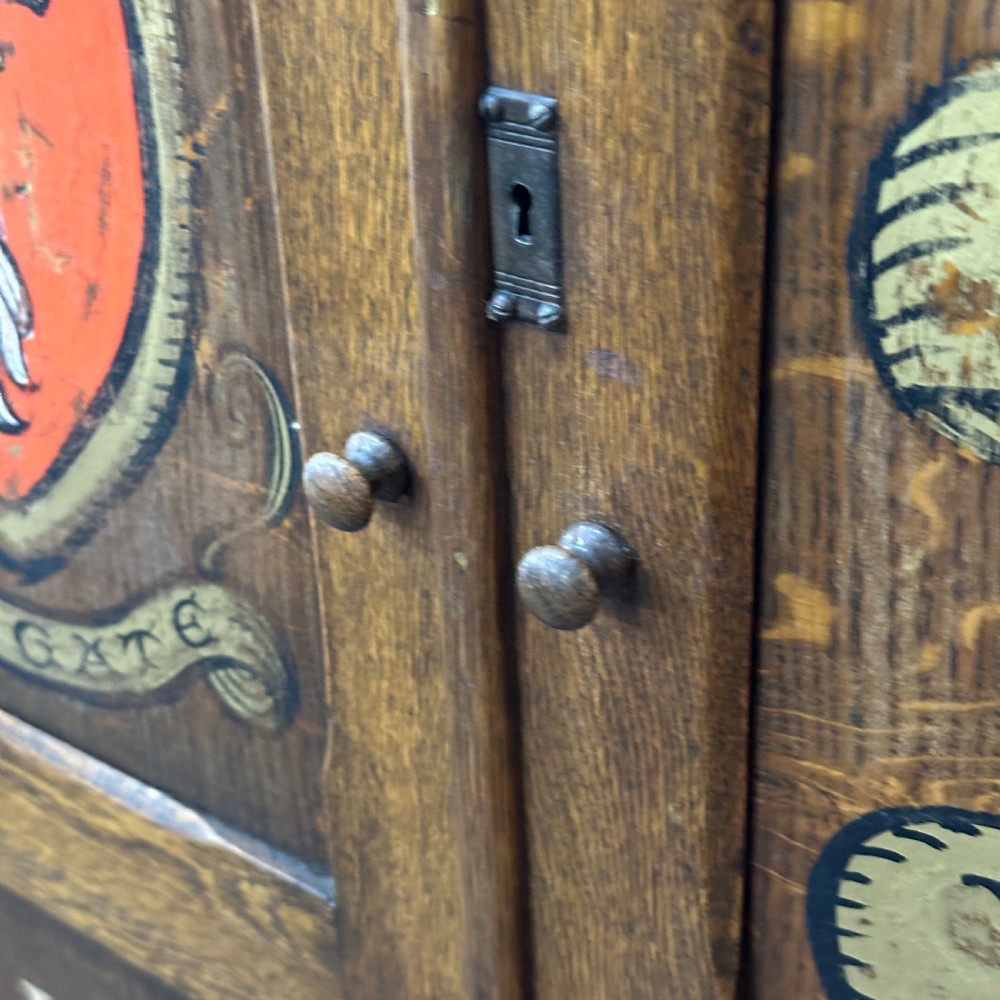 A vintage 1930s oak school cabinet featuring two doors with hand-painted institutional lettering and a crest. View VII
