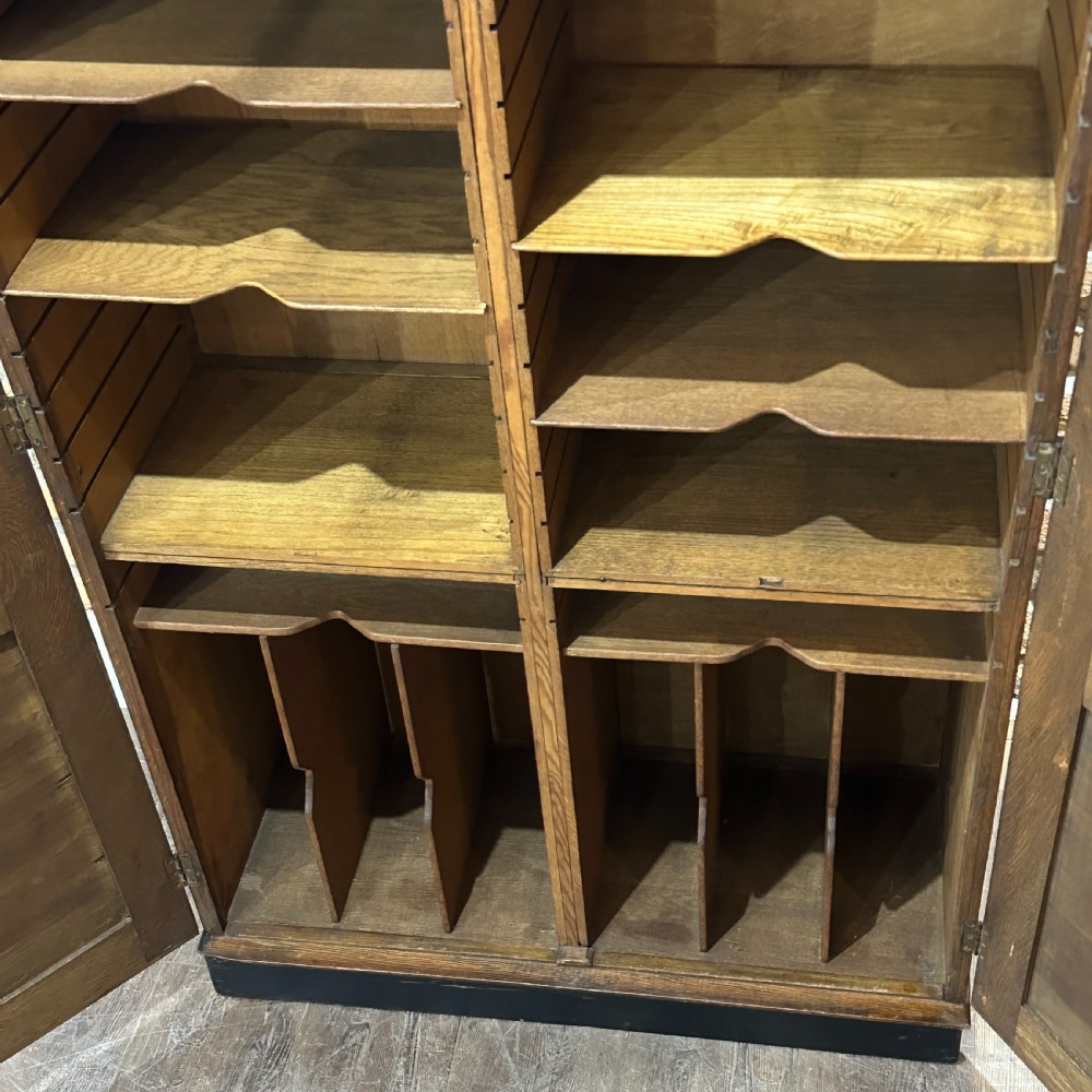 A vintage 1930s oak school cabinet featuring two doors with hand-painted institutional lettering and a crest. View VIII