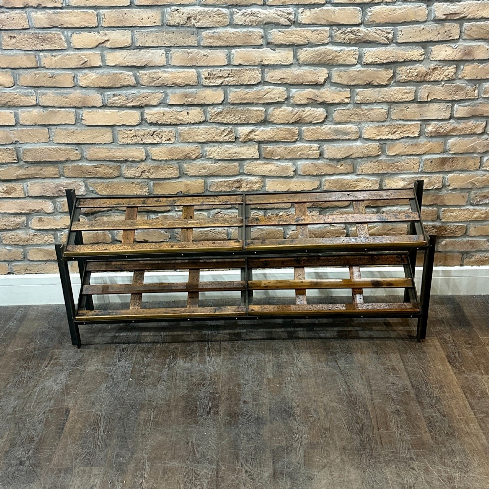 A two-tier vintage shop display counter featuring slatted oak shelves set within a dark metal frame with bronze detailing.