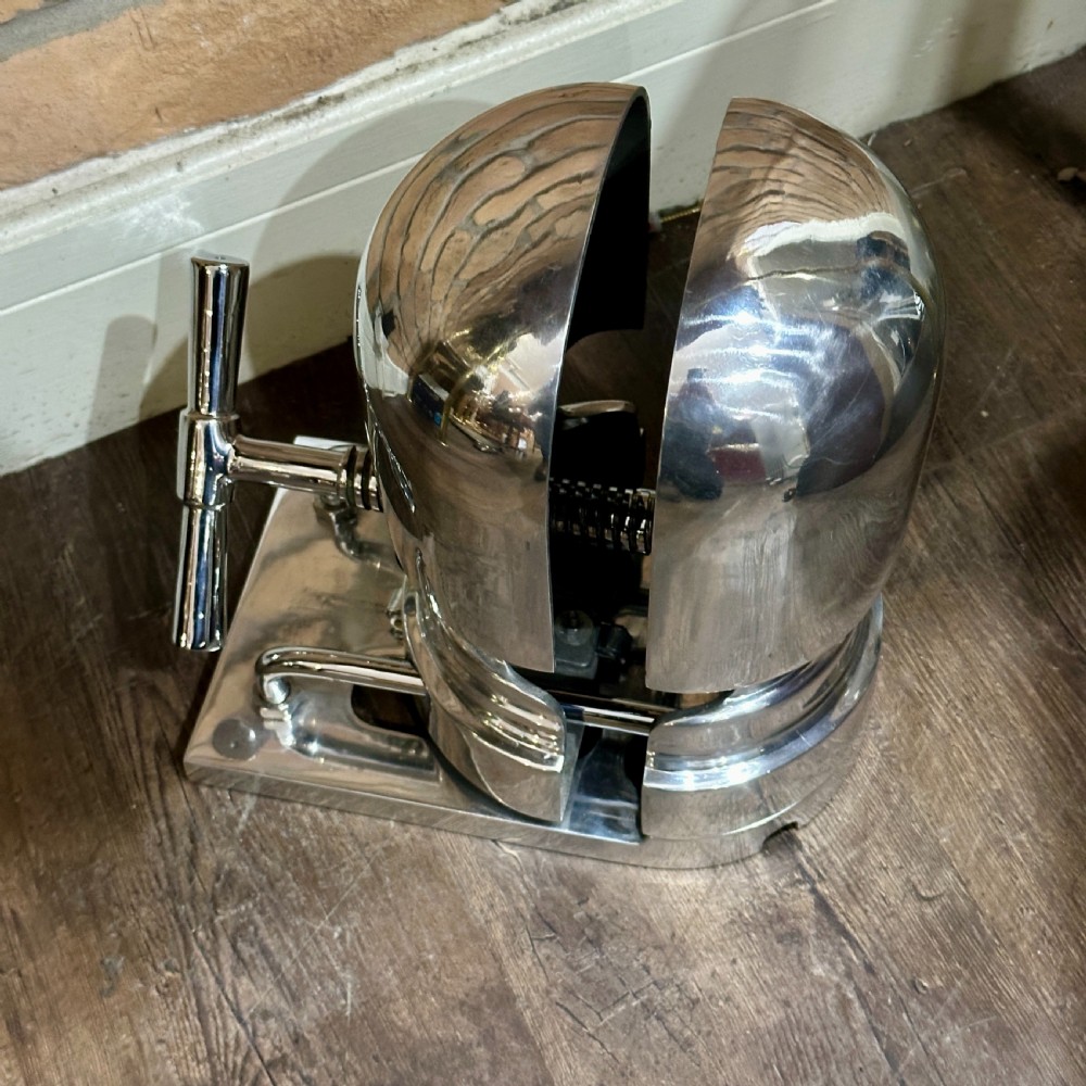 A restored 1930s polished aluminium mechanical hat stretcher with a turn handle set on a solid metal base. View V