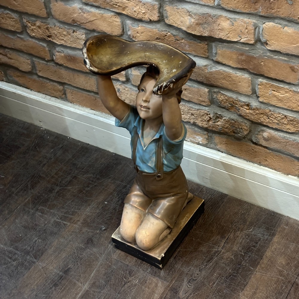 A hand-painted 1920s plaster sculpture of a kneeling boy wearing a blue shirt and brown shorts, supporting a shell-shaped tray overhead. View III