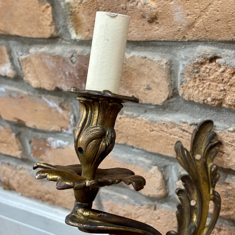 A pair of gilt brass two-arm wall sconces featuring ornate Rococo scrollwork and acanthus leaf decoration. View III