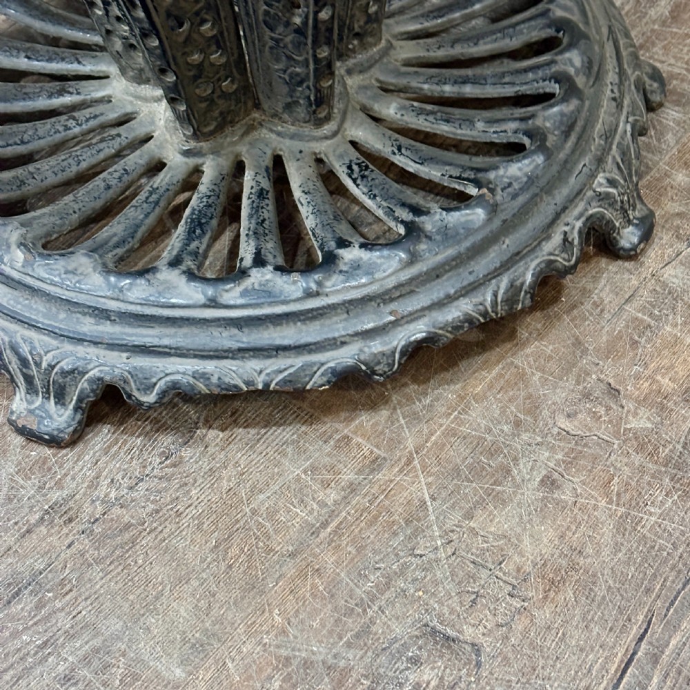 A black cast iron umbrella stand shaped like a folded umbrella with a central shaft ending in a fist handle, set on a circular fluted base. View II