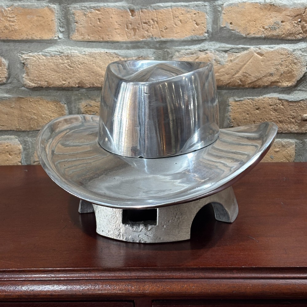 A cast aluminium milliners hat block mould shaped like a broad-brimmed cowboy hat with a polished silver metallic finish.