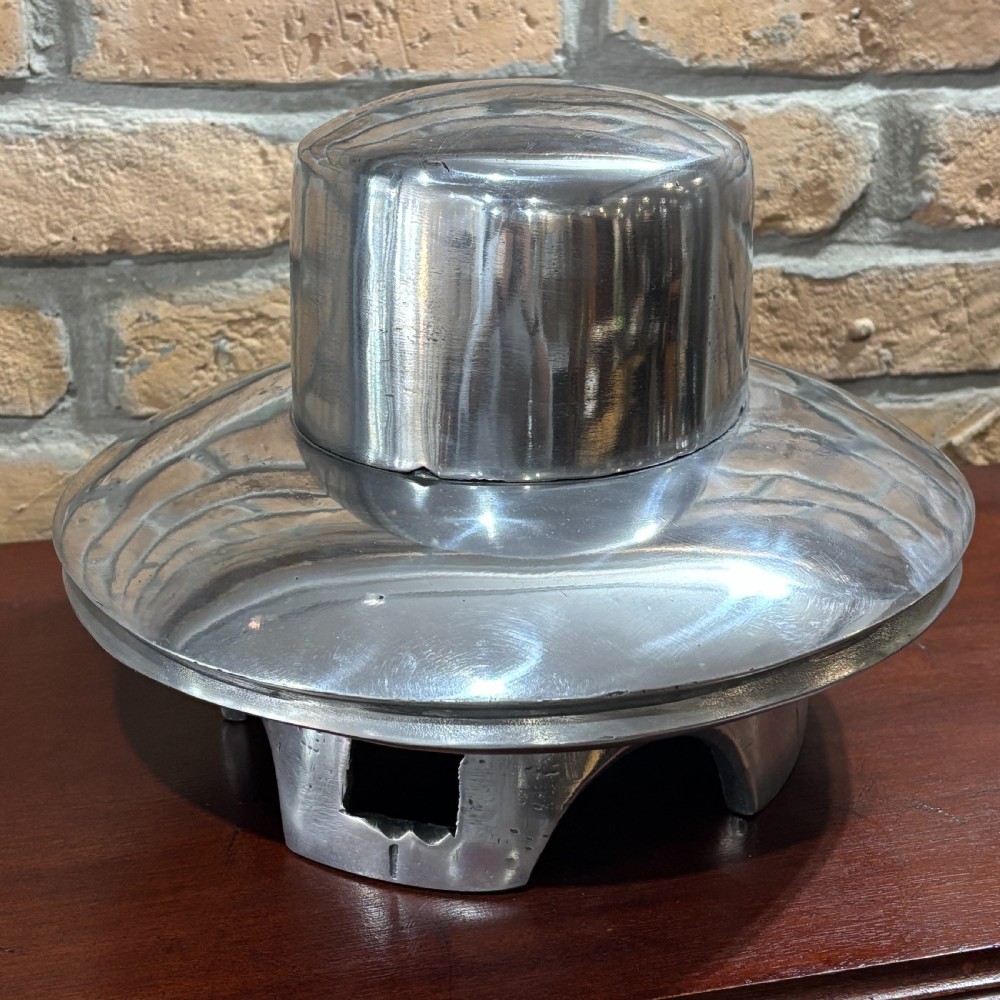 A polished silver cast aluminium milliners hat mould featuring a rounded crown section and flared brim contour resting on a hollow base.