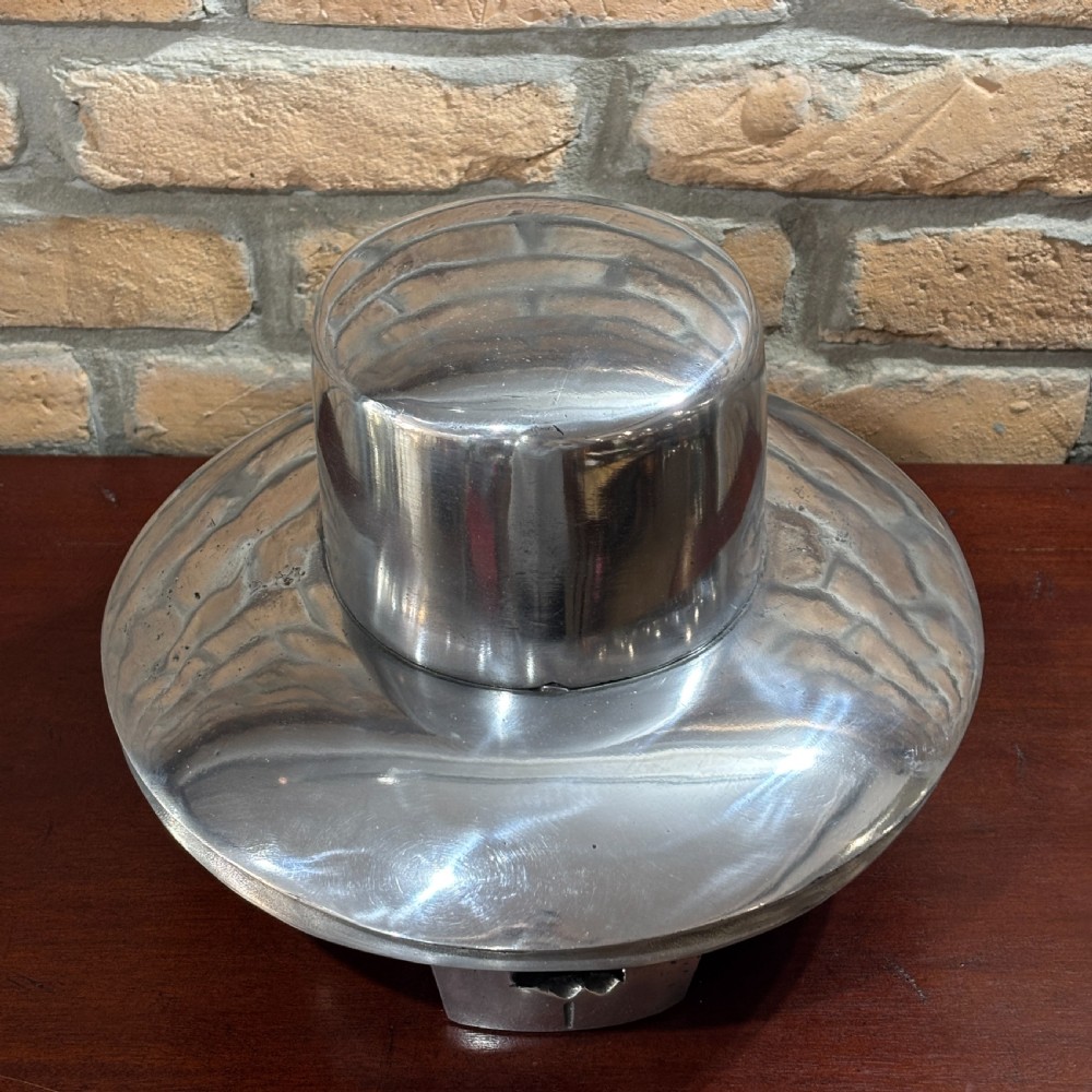 A polished silver cast aluminium milliners hat mould featuring a rounded crown section and flared brim contour resting on a hollow base. View III