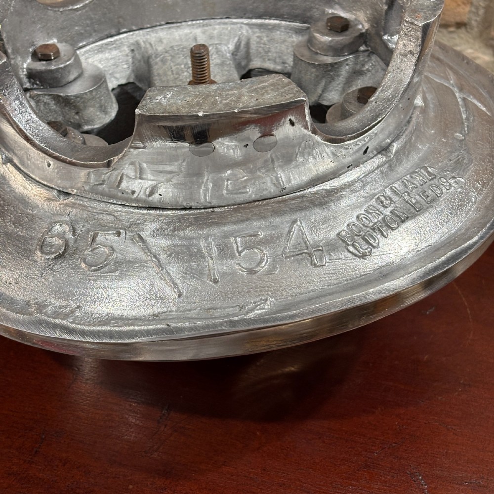 A polished cast aluminium milliners hat block mould featuring a fedora crown and wide brim mounted on a hollow metallic base. View VI