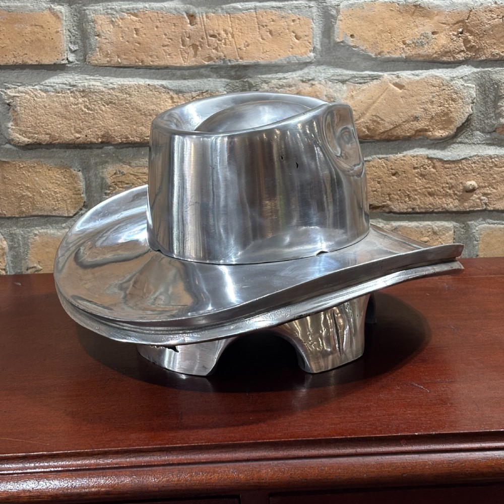A polished silver aluminium milliners hat block mould shaped in a fedora brim silhouette.