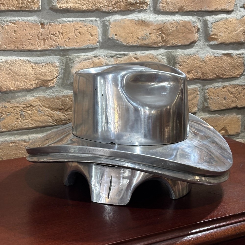 A polished silver aluminium milliners hat block mould shaped in a fedora brim silhouette. View V