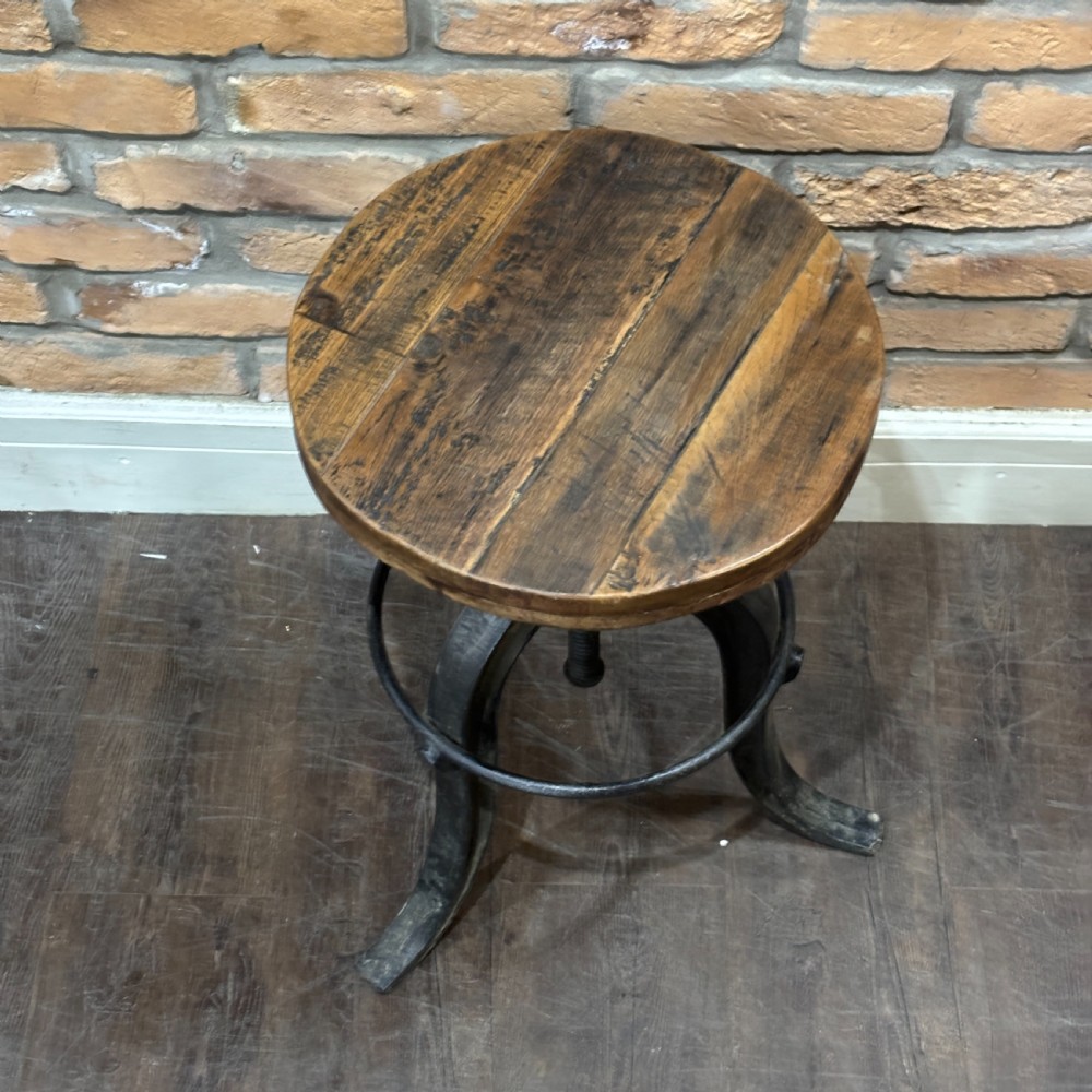 An adjustable industrial workshop stool featuring a circular dark wood seat supported by a black cast iron tripod base with a central screw mechanism and circular footrest. View II