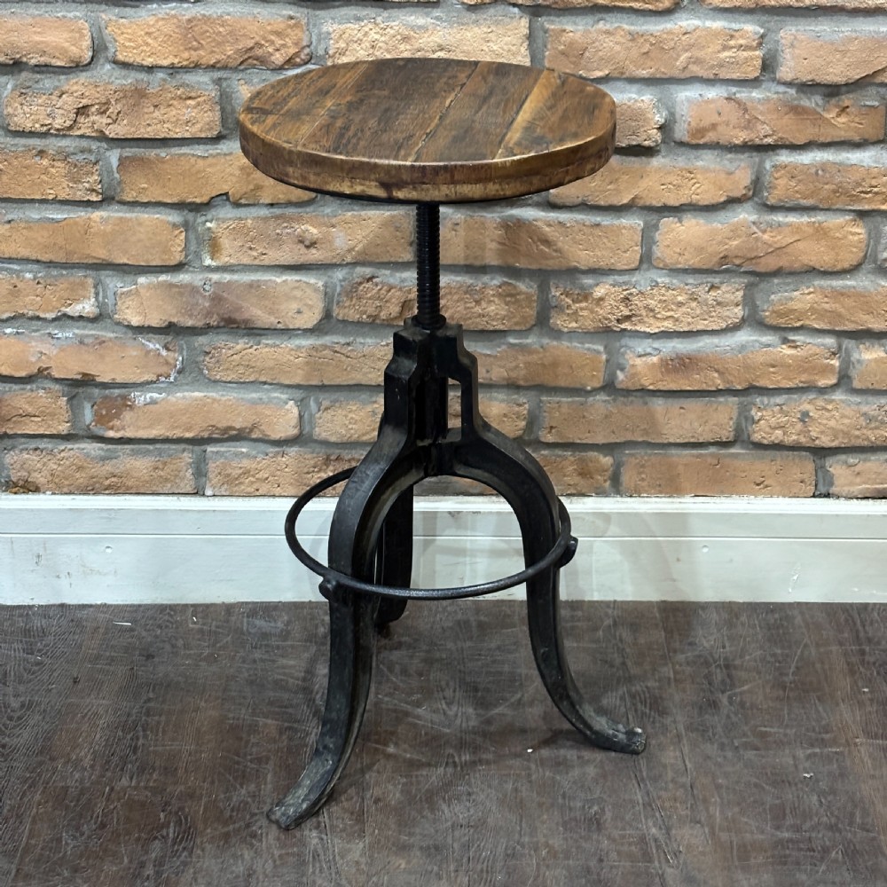 An adjustable industrial workshop stool featuring a circular dark wood seat supported by a black cast iron tripod base with a central screw mechanism and circular footrest. View IV
