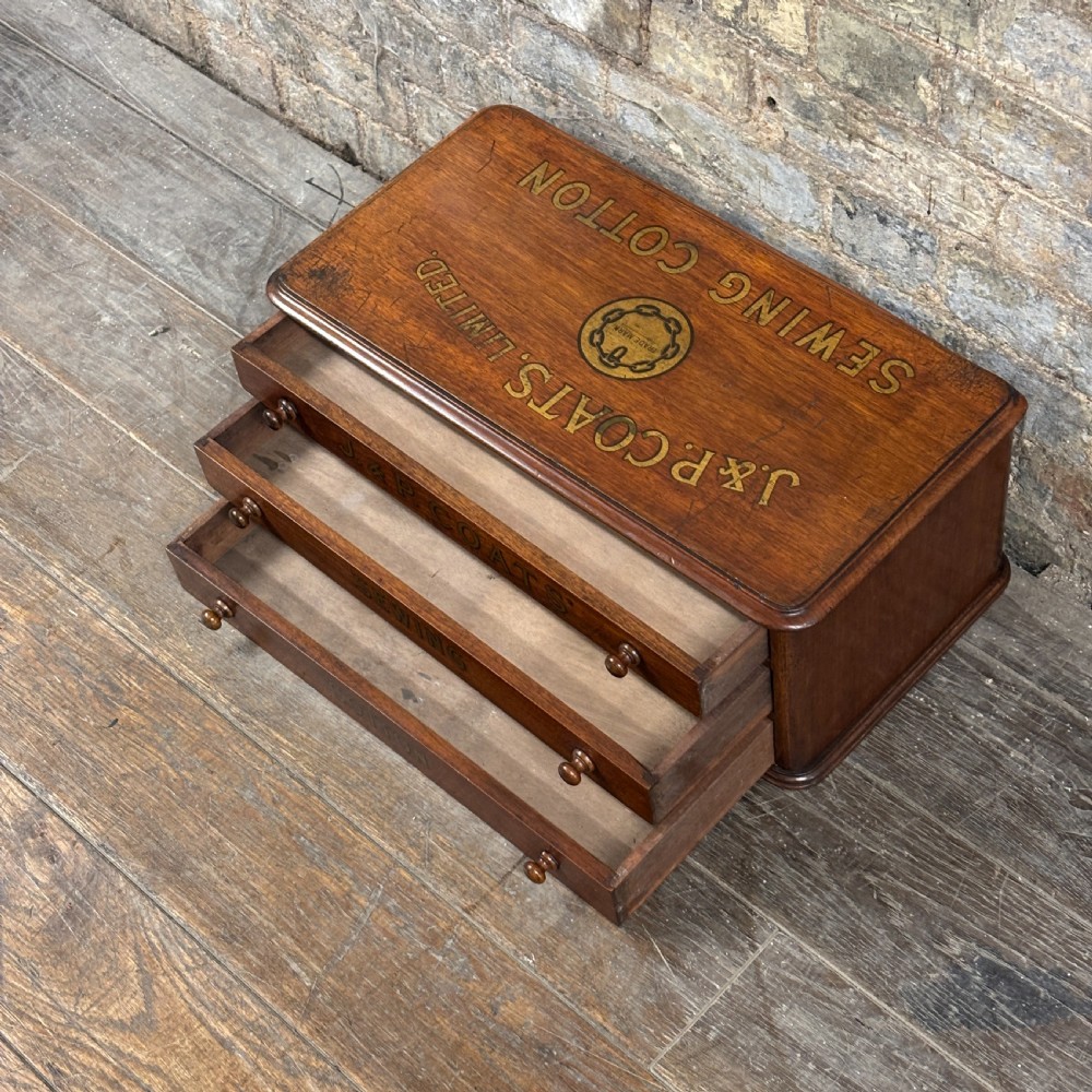 An antique wooden J. & P. Coats countertop drawer unit with stencilled lettering on the drawers and top surface. View II