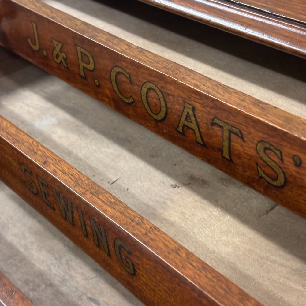 An antique wooden J. & P. Coats countertop drawer unit with stencilled lettering on the drawers and top surface. View III