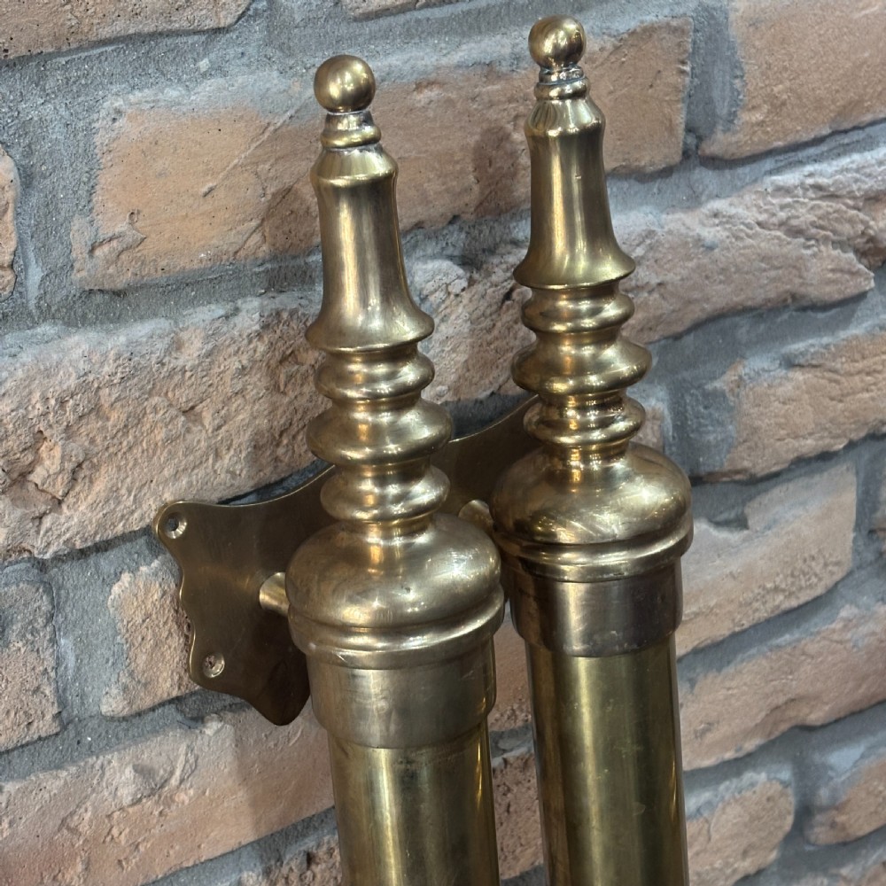 A pair of long tubular brass shop door handles featuring turned finials on each end and side mounting brackets. View II
