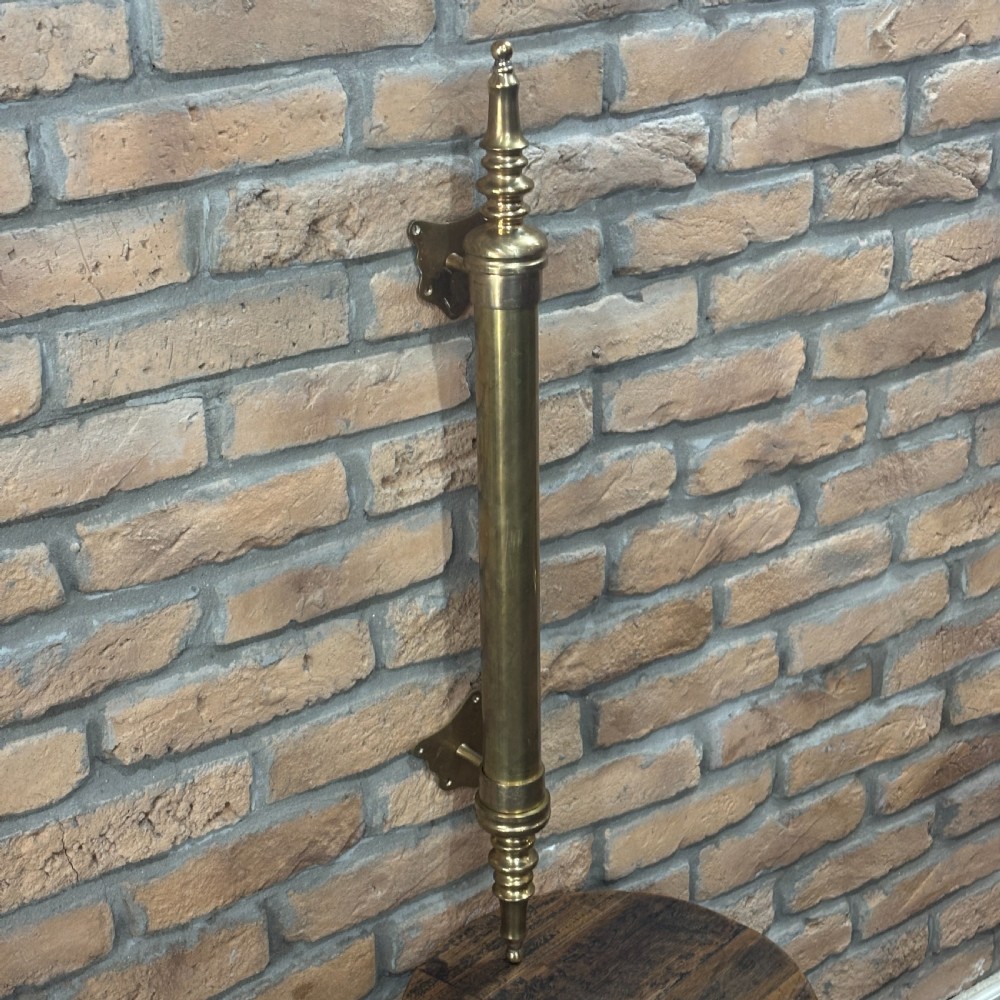 A pair of long tubular brass shop door handles featuring turned finials on each end and side mounting brackets. View III