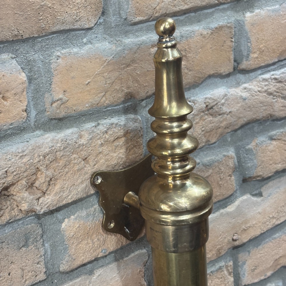 A pair of long tubular brass shop door handles featuring turned finials on each end and side mounting brackets. View IV