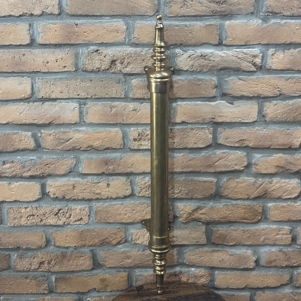A pair of long tubular brass shop door handles featuring turned finials on each end and side mounting brackets. View V