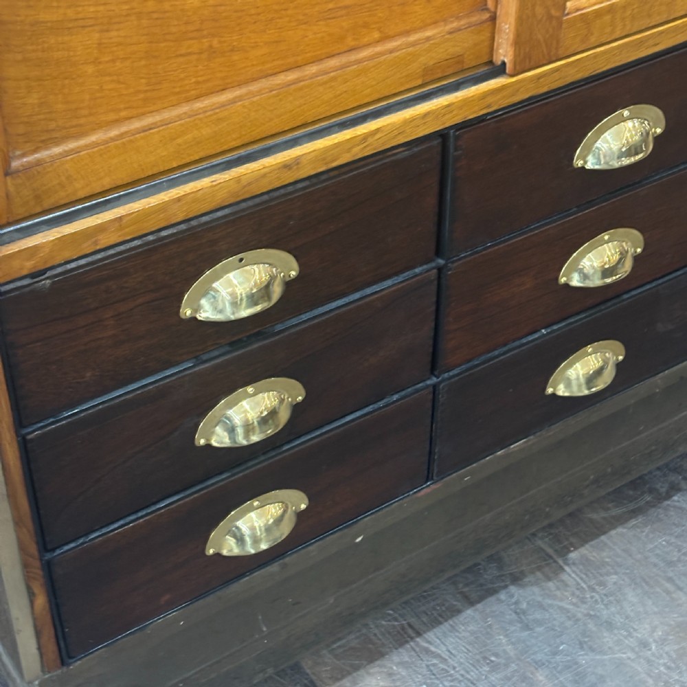 A 1930s brass-framed shop display counter featuring glass side and top panels, tiered interior timber display bins, and timber sliding back doors. View III