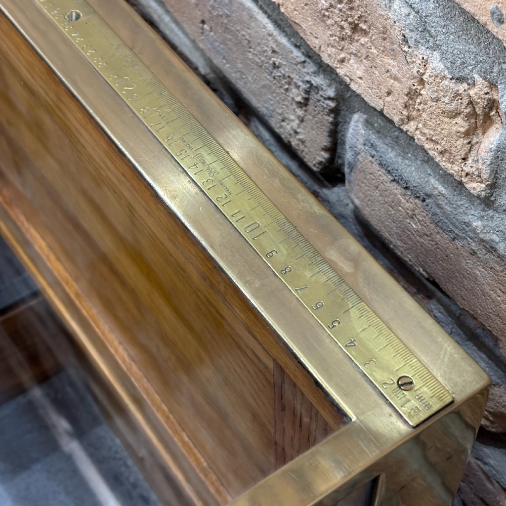A 1930s brass-framed shop display counter featuring glass side and top panels, tiered interior timber display bins, and timber sliding back doors. View VI