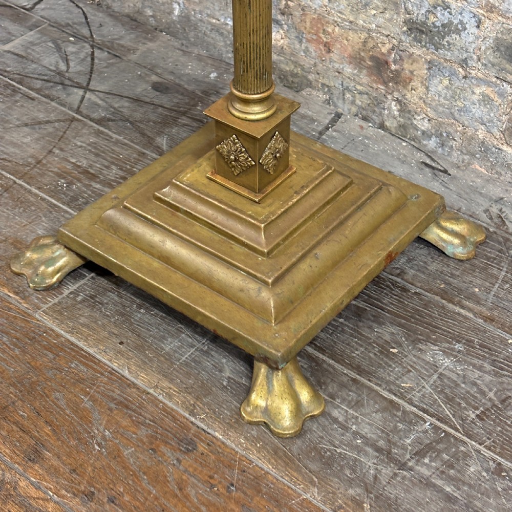 An antique Edwardian brass standard lamp featuring a fluted column, classical capital, and a stepped square base resting on cast claw feet. View II