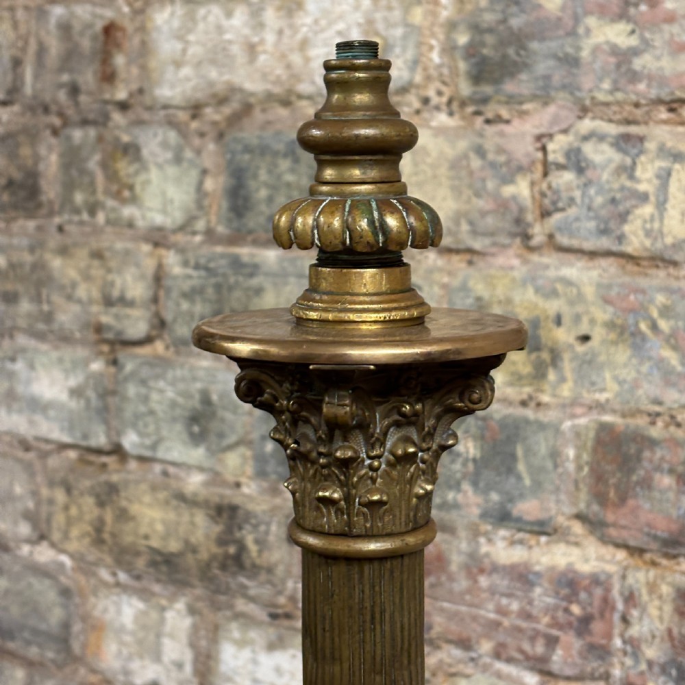 An antique Edwardian brass standard lamp featuring a fluted column, classical capital, and a stepped square base resting on cast claw feet. View III