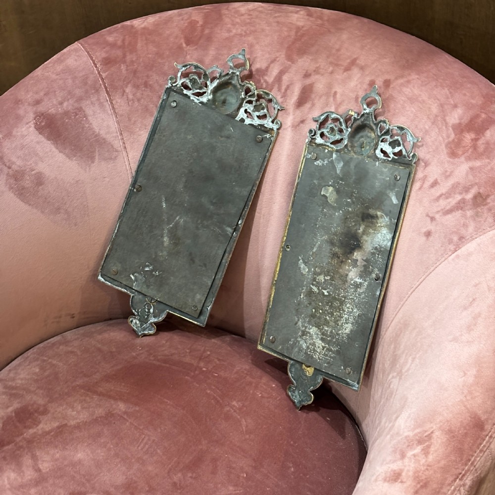A pair of rectangular brass wall mirrors featuring ornate classical mask crestings, floral garlands, and scrolled detailing. View VI