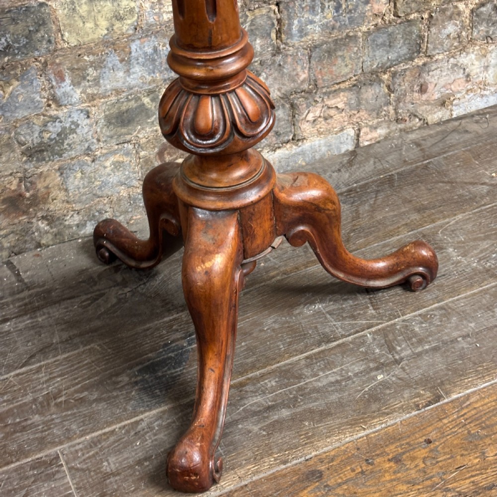 A Victorian mahogany shaving stand featuring a circular tilting mirror mounted above a blue fabric-lined shelf, supported by a turned column and tripod scroll legs. View III