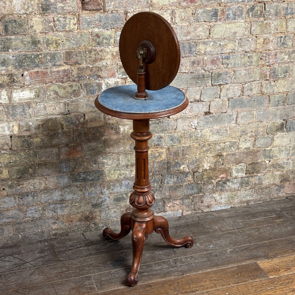 A Victorian mahogany shaving stand featuring a circular tilting mirror mounted above a blue fabric-lined shelf, supported by a turned column and tripod scroll legs. View IV
