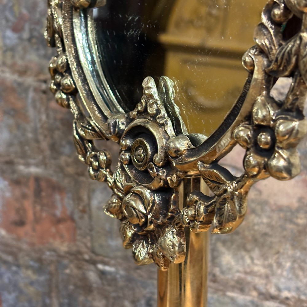 An ornate 1930s cast brass dressing table mirror with detailed floral scrollwork, an oval mirror frame, and a sturdy pedestal base. View III