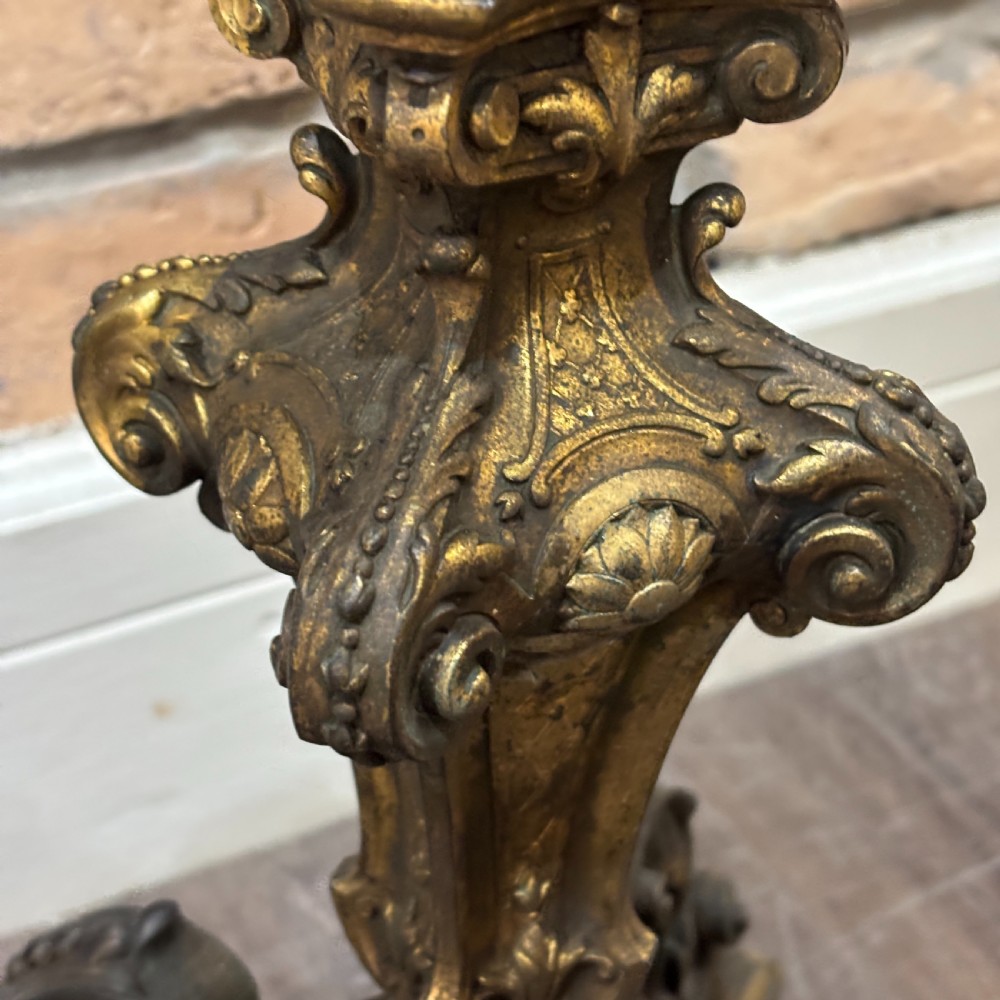 A pair of late Victorian gilt bronze lamp bases featuring ornate scrolling foliate designs, tripod feet, and raised brass light sockets. View V