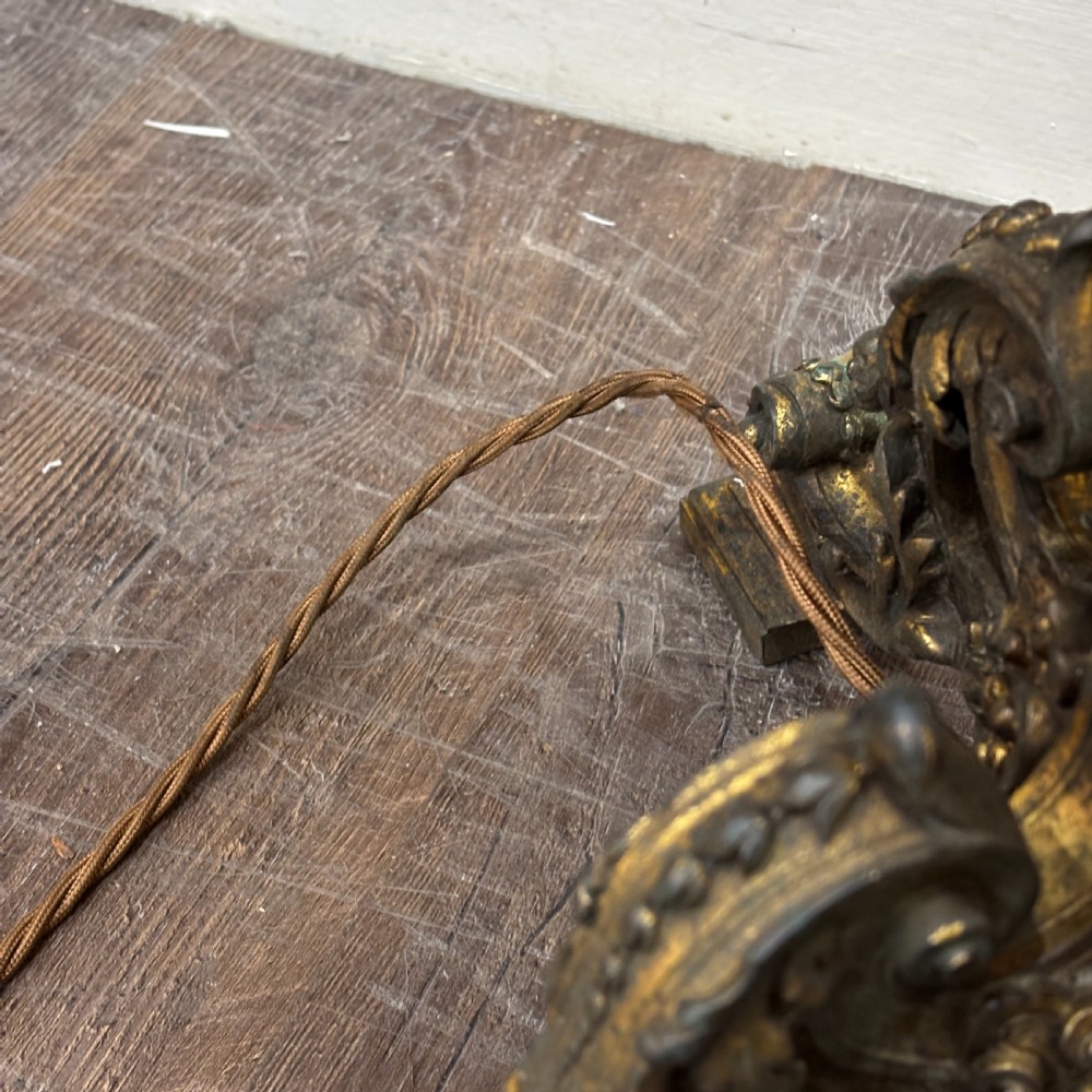 A pair of late Victorian gilt bronze lamp bases featuring ornate scrolling foliate designs, tripod feet, and raised brass light sockets. View VII