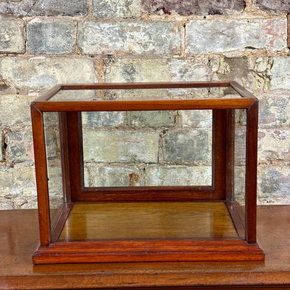 A rectangular 1920s countertop display cabinet featuring a polished mahogany frame with clear glass panels on all sides.