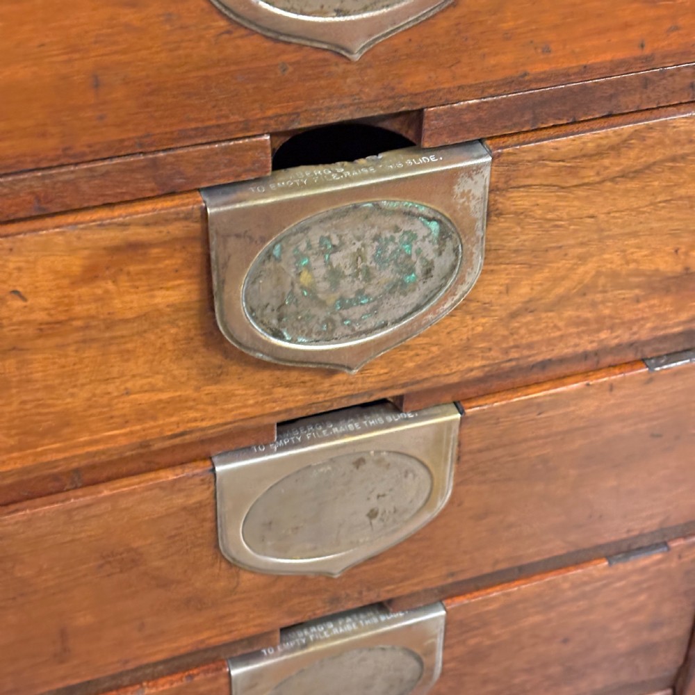 An Edwardian oak Ambergs patent letter filing cabinet featuring three vertical columns of ten small drawers fitted with brass label holders. View VI