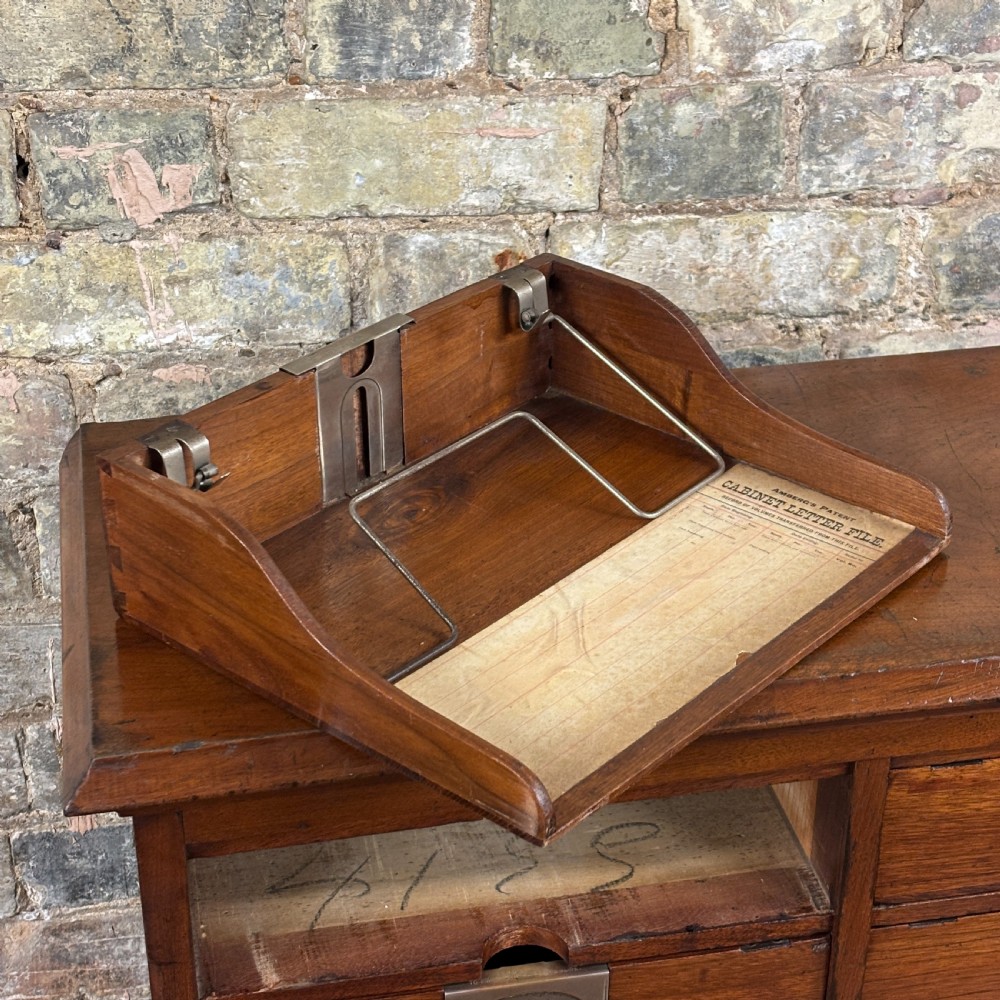 An Edwardian oak Ambergs patent letter filing cabinet featuring three vertical columns of ten small drawers fitted with brass label holders. View IX