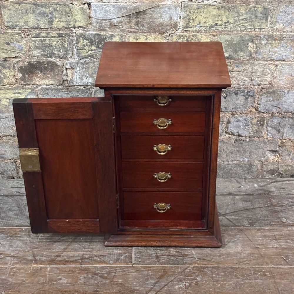 A compact dark mahogany tabletop cabinet featuring a single recessed panel door with a keyhole, a slanted top, and a stepped plinth base. View II