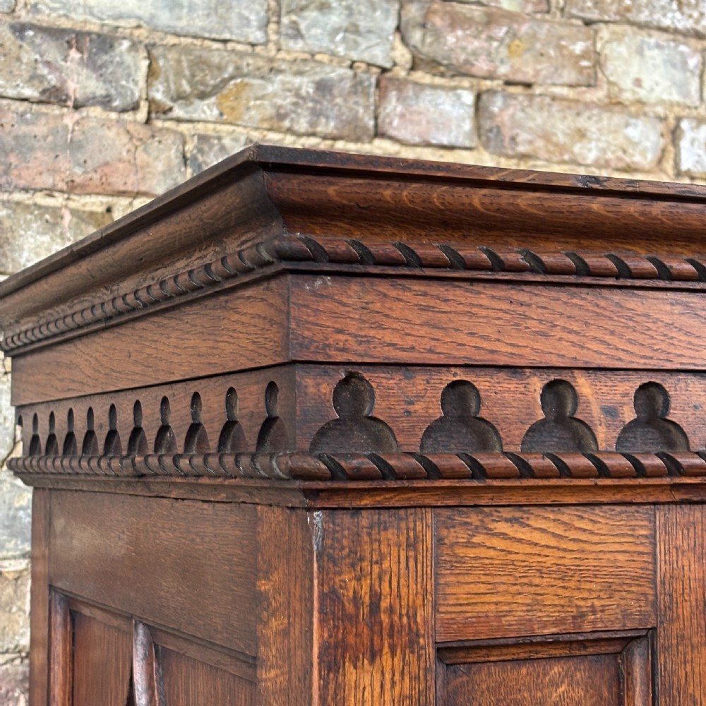 A late Victorian oak cabinet with pointed Gothic arch moulding on two upper panelled doors, two middle drawers, and a lower double-door cupboard. View IV