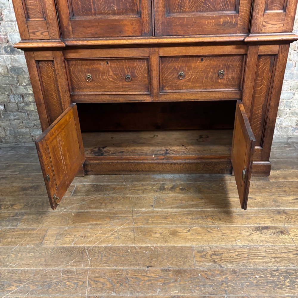A late Victorian oak cabinet with pointed Gothic arch moulding on two upper panelled doors, two middle drawers, and a lower double-door cupboard. View IX