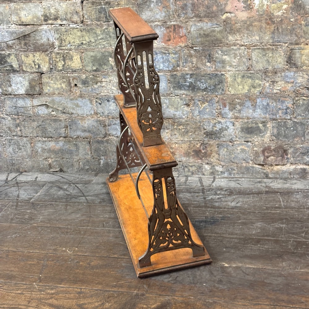 A two-tier antique paper roll dispenser featuring warm brown wooden shelves supported by cast metal side brackets and spring bars. View III