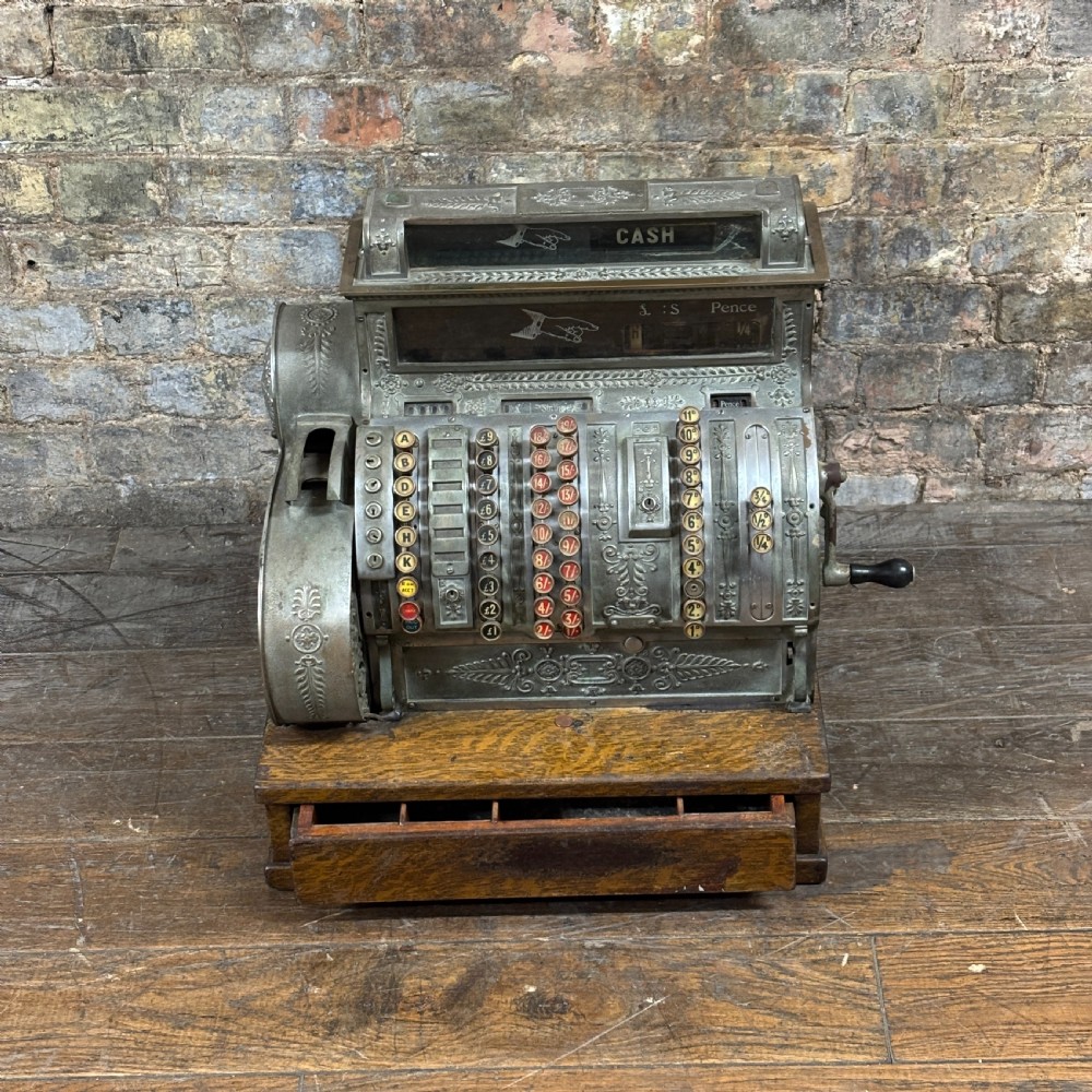 An early twentieth-century mechanical cash register featuring a cast metal case on a wooden base with an open currency drawer.
