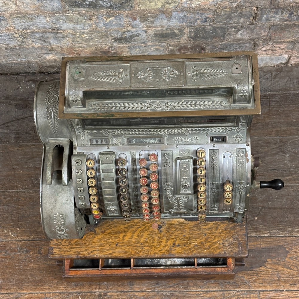 An early twentieth-century mechanical cash register featuring a cast metal case on a wooden base with an open currency drawer. View II