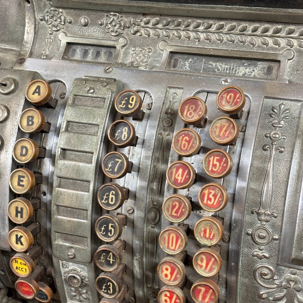 An early twentieth-century mechanical cash register featuring a cast metal case on a wooden base with an open currency drawer. View III